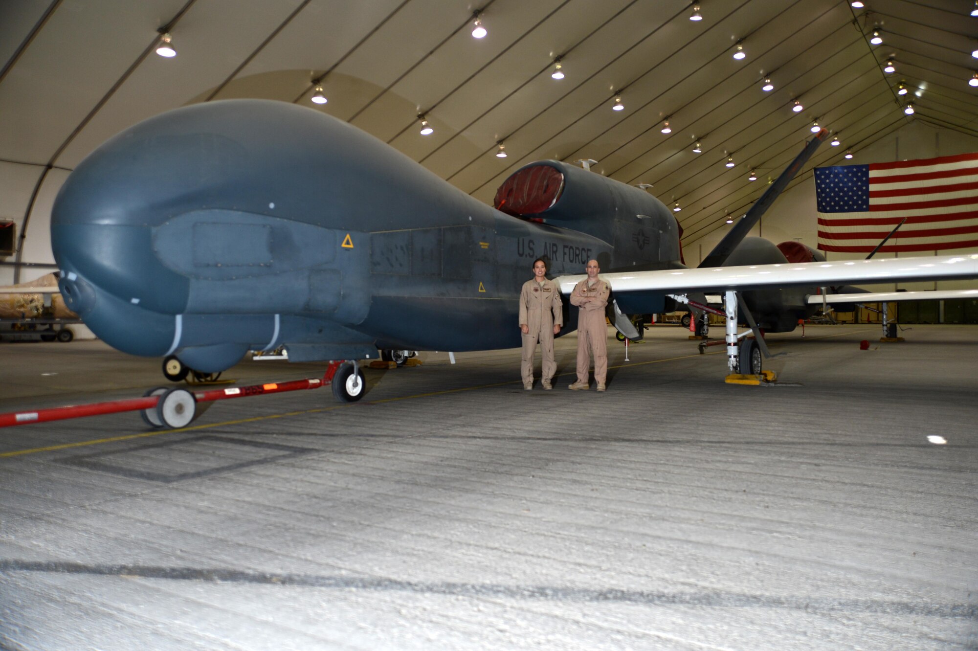 U.S. Air Force Lt. Col. Steve, 99th Expeditionary Reconnaissance Squadron commander, and Capt. Marie, 99 ERS RQ-4 pilot, stand in front of an EQ-4 Global Hawk unmanned aircraft at an undisclosed location in Southwest Asia, Nov. 11, 2015. Steve and Marie piloted the Global Hawk during the initial launch and recovery portions of the airframe’s 500th sortie in support of Operation Inherent Resolve.  (U.S. Air Force photo by Tech. Sgt. Frank Miller/Released)