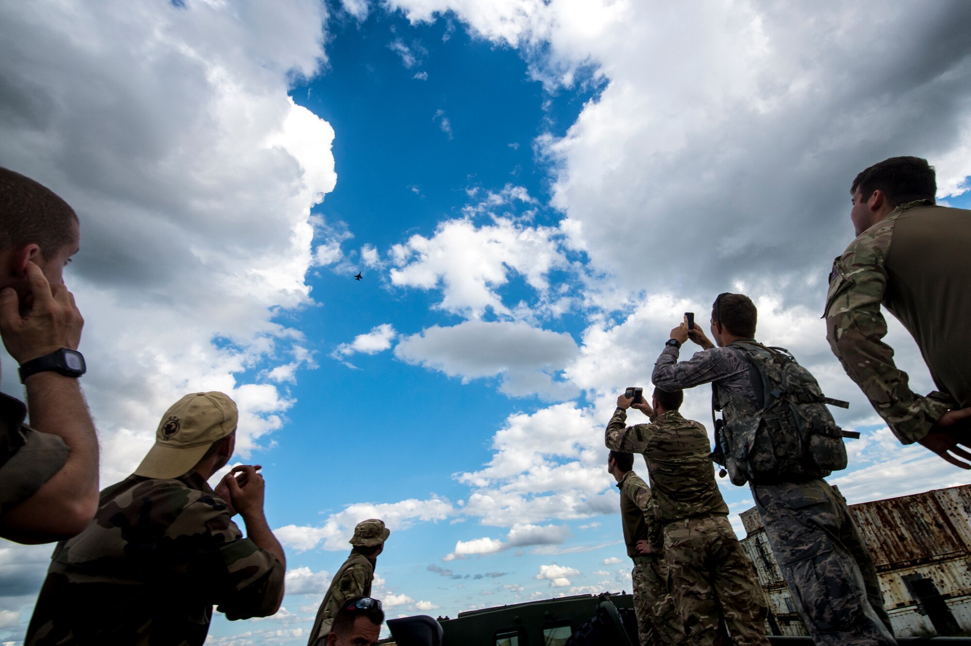U.S., French and Royal Air Force Airmen watch and take pictures as an F-16C Fighting Falcon flies overhead during exercise GLOBAL EAGLE, Oct. 29, 2015, at Avon Park Air Force Range, Fla. F-16C’s were on station to assist in training objectives for the 93d Air Ground Operations Wing and exercise GLOBAL EAGLE. (U.S. Air Force photo by Senior Airman Ryan Callaghan/Released)
