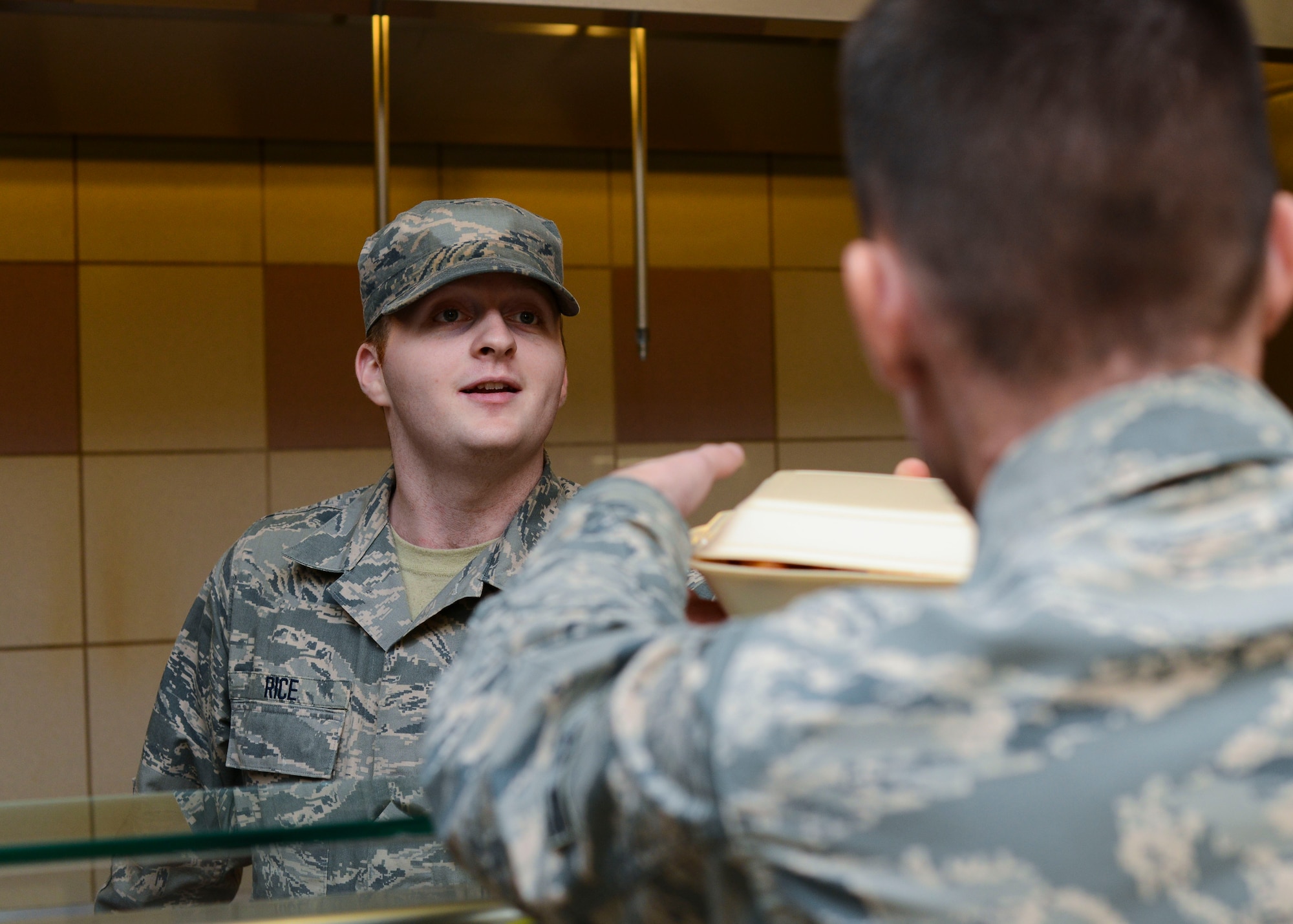U.S. Air Force Senior Airman Robert Rice, 31st Force Support Squadron food services journeyman, hands a customer his meal, Nov. 10, 2015, at Aviano Air Base, Italy. During this renovation period, Airmen will experience changes in DFAC hours and services. For more information, click here or call the DFAC at 632-8206. (U.S. Air Force photo by Senior Airman Austin Harvill/Released)