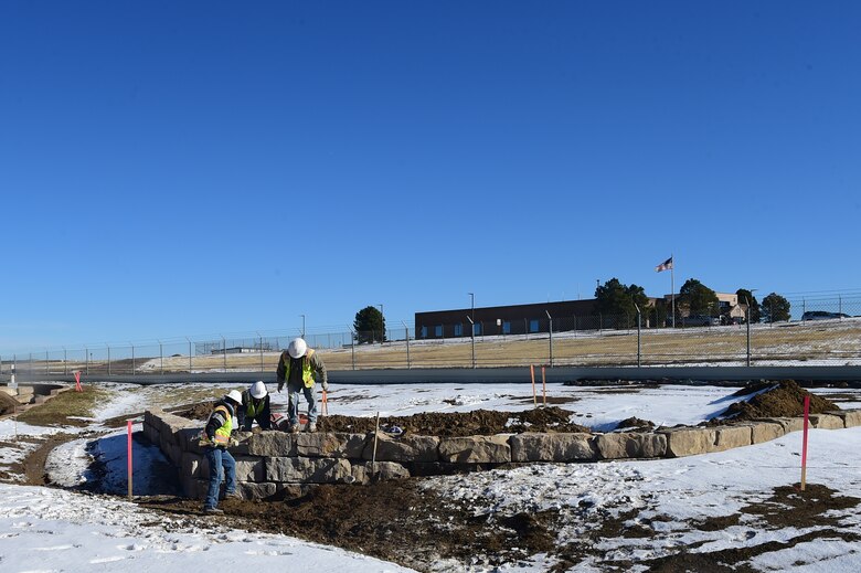 Workers from Mountain Splendor Service Inc. use rock to form a platform Nov. 12, 2015, at Buckley Air Force Base, Colo. The rocks are being installed to provide a stable platform for a new entrance sign to Buckley AFB at the Mississippi Gate. (U.S. Air Force photo by Airman Luke W. Nowakowski/Released)