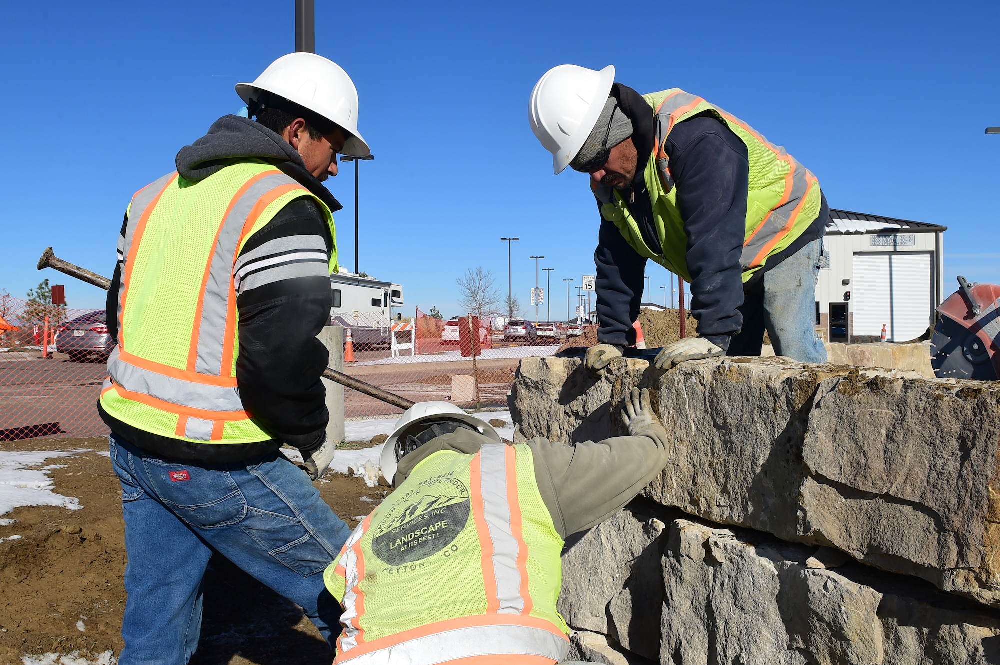 Workers from Mountain Splendor Service Inc. orient rocks to form a platform Nov. 12, 2015, at Buckley Air Force Base, Colo. The rocks are being installed to provide a stable platform for a new entrance sign to Buckley AFB at the Mississippi Gate. (U.S. Air Force photo by Airman Luke W. Nowakowski/Released)