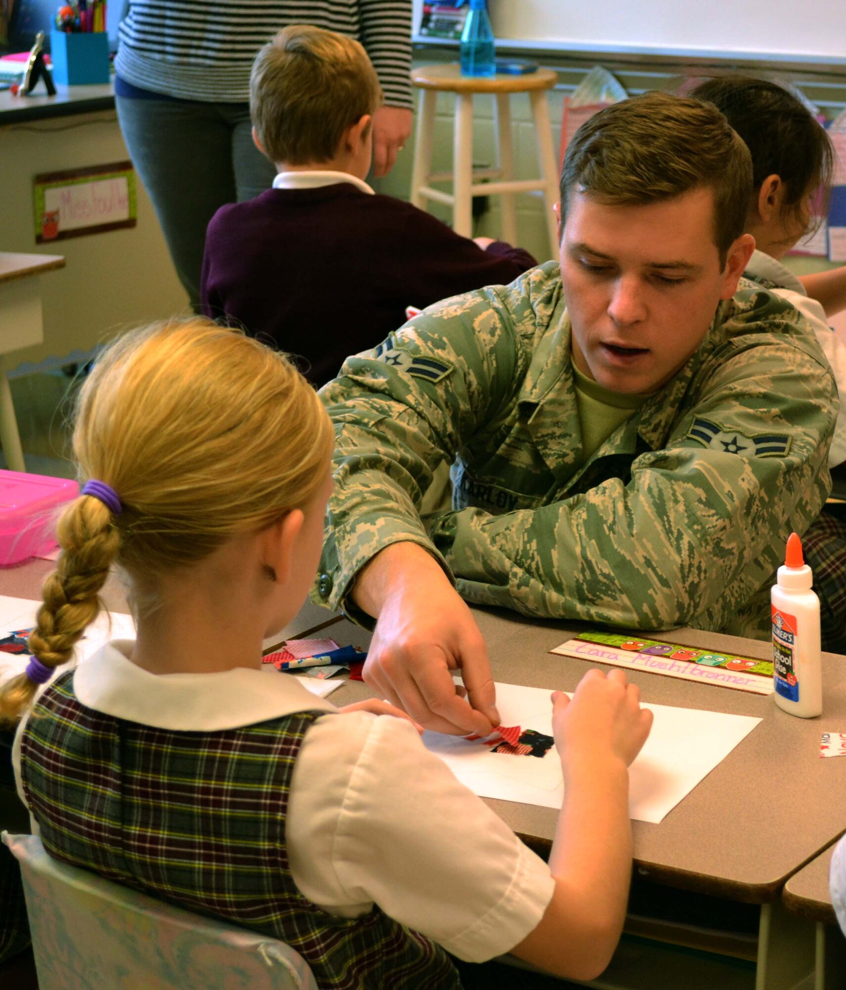 Airman 1st Class Igor Karlov, a supply technician with the 111th Logistics Readiness Squadron at Horsham Air Guard Station, Pennsylvania, helps a second-grade student from Mary, Mother of the Redeemer Catholic School in North Wales, Pennsylvania, with a patriotic-themed craft Nov. 10, 2015. 111th Attack Wing members and associated Wing civilian volunteers partnered with the school in an event intended help students develop into moral, civic, and good-mannered community members. (U.S. Air National Guard photo by Tech. Sgt. Andria Allmond/Released)