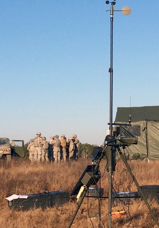 Airmen from the 15th Operational Weather Squadron and the 18th Weather Squadron gather for instruction during a recent five day field training exercise at Fort Campbell, Kentucky. In the foreground stands a Tactical Meteorological Observing System. (U.S. Air Force courtesy photo)