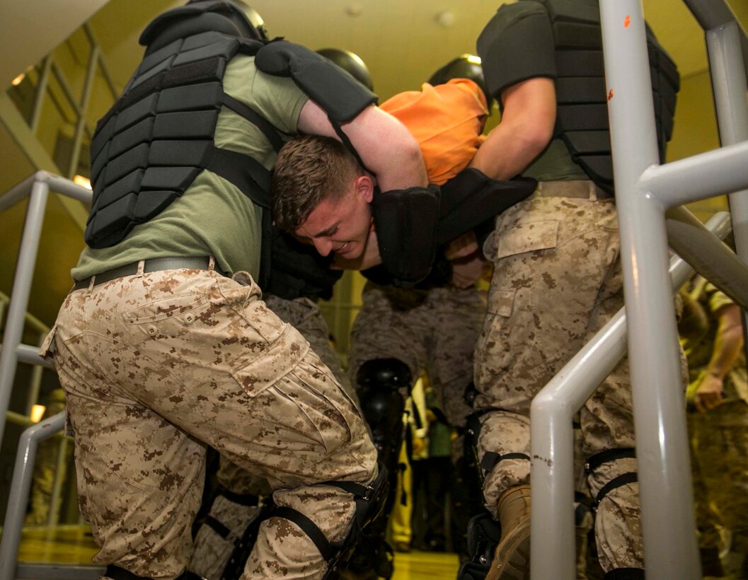 Lance Cpl. Jesse Gilmour poses as an inmate during a demonstration of how to handle an unruly inmate, during Okinawa Prefectural Police Department’s tour through the Marine Corps Installation Pacific Brig on Camp Hansen, Okinawa, Japan, Oct. 22, 2015. The demonstration showed how guards properly take down and restrain an out-of-control inmate. The unruly inmate is then placed into a restraint chair where he is given four hours to calm down. If the inmate persists to show aggression after four hours, a medical officer must check on the inmate before proceeding for another four hours. Gilmour is from Jupiter, Florida, and is a corrections specialist with Bravo Company, Headquarters and Service Battalion, Marine Corps Installations Pacific.