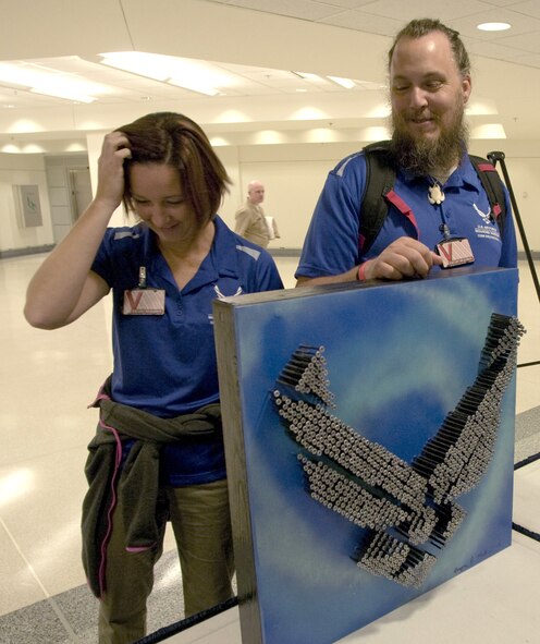 Former Staff Sgt. Gregory Miller, right, and his wife Heather share a laugh while he shows his mixed media pieces during a healing arts event Nov. 12 at the Pentagon. Miller and other wounded military members were recognized for their work as part of a healing arts program created by the Defense Department and the National Endowment for the Arts to offer art therapy to recovering troops. (U.S. Air Force photo/Sean Kimmons)