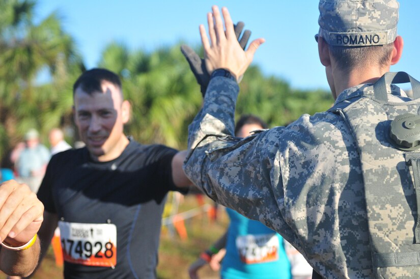 Spc. Rafaello Romano, with the 377th Theater Sustainment Command, high fives a Tough Mudder competitor at the start line of the Central Florida Tough Mudder in Palm Bay, Fla., Nov. 7. The Tough Mudder brings people together to engage in a series of challenges that not only pushes participants to their physical limits, but also tests their mental grit to get through the obstacles. (U.S. Army Reserve Photo by Sgt. Bethany L. Huff)