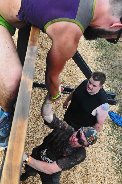 Tough Mudder competitors help each other overcome the Berlin Wall during the Central Florida Tough Mudder in Palm Bay, Fla., Nov 7. The Tough Mudder brings people together to engage in a series of challenges that not only pushes participants to their physical limits, but also tests their mental grit to get through the obstacles.