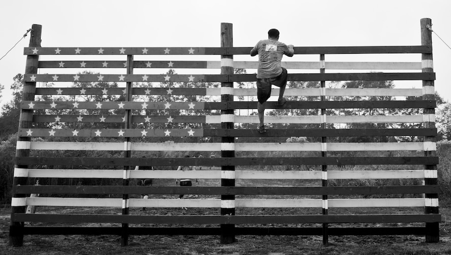 A competitor climbs the American flag obstacle during the Pensacola Mud Run Oct 24. Active duty and reserve service members from many local military bases came out to get dirty in the five-mile, 20-obstacle challenge.  (U.S. Air Force photo/Tech. Sgt. Sam King) 
