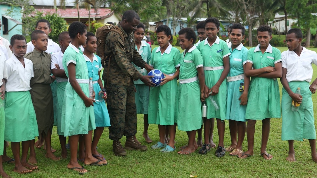 Petty Officer 2nd Class Olusola Adeyemo, a hospital corpsmen for KOA MOANA 15-3, delivers a soccer ball to children of a small village in Namosi Province, Fiji, Oct. 13. Marines and sailors participated in community rebuilding projects throughout the day and learned customs and traditions from the local people. 