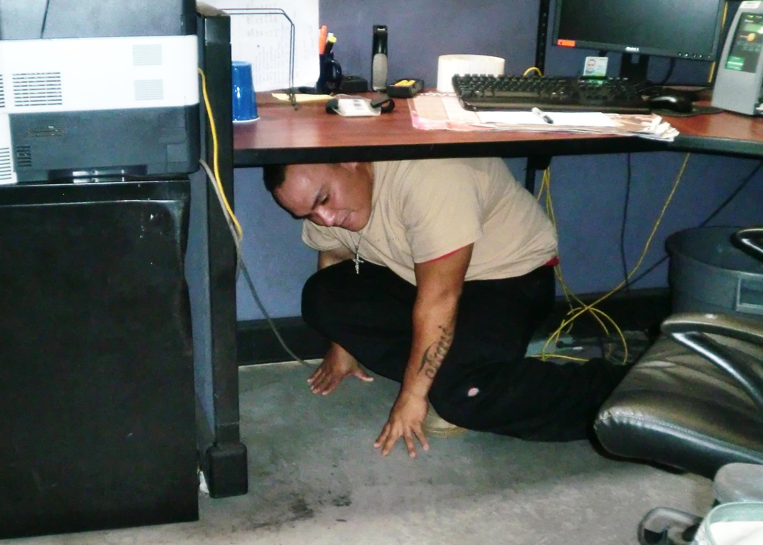 An employee practices the “hide” response during an active shooter exercise at DLA Distribution Guam, Marianas. 