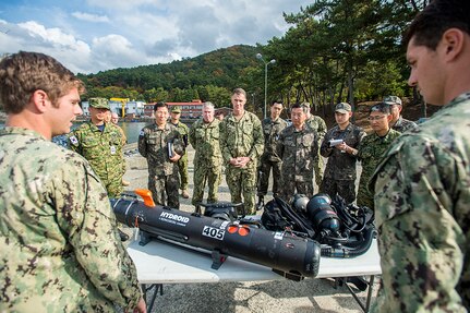 CHINHAE (Nov. 12, 2015) - Lt. Jeffery Burton, left, assigned to Explosive Ordnance Disposal Mobile Unit (EODMU) 5, explains the mission and tools used by his Very Shallow Water (VSW) platoon to Rear Adm. Bill Byrne, commander, U.S. Naval Forces Korea, during Exercise Clear Horizon on Commander Fleet Activities Chinhae. Exercise Clear Horizon is an annual bilateral exercise between the U.S. and Republic of Korea navies that focus on increasing capabilities and coordination between ships, and aircraft in mine countermeasures in international waters surrounding the Korean peninsula. 