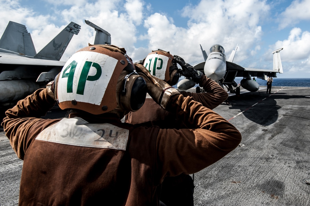 U.S. sailors signal a pilot to test the vertical stabilizers of an F/A-18E Super Hornet during a preflight test on the flight deck of the U.S. Navy's only forward-deployed aircraft carrier USS Ronald Reagan in the Philippine Sea, Nov. 13, 2015. The Reagan and Carrier Air Wing provide a combat-ready force to protect and defend the collective maritime interests of the U.S. and its allies and partners in the Indo-Asia-Pacific region. U.S. Navy photo by Petty Officer 3rd Class Nathan Burke
