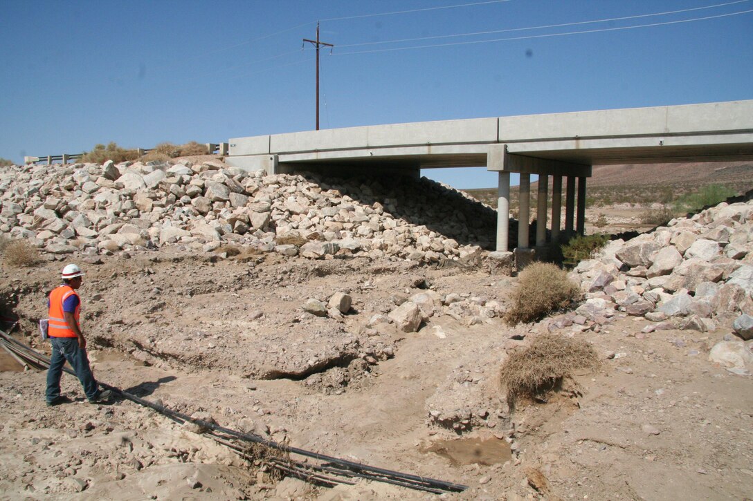 A USACE engineer inspects bridge support and channel after passing monsoon storm hit the Fort Aug. 26, 2013. The photo depicts the damge to the area before it's repair