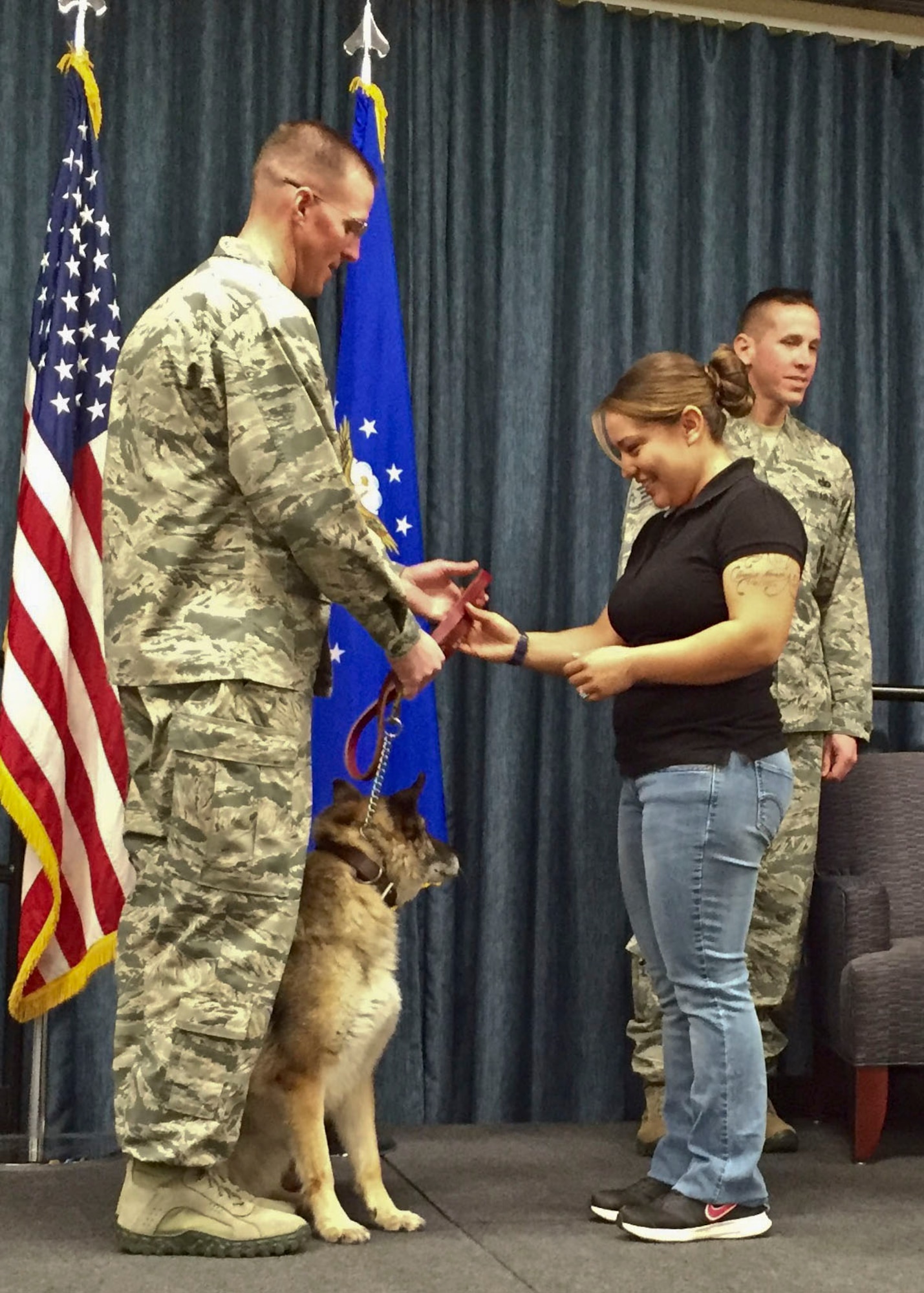 Staff Sgt. Adrianne Archuleta, 92nd Security Forces Squadron military working dog handler, accepts the leash for MWD Helena, from Maj. Kevin McMahon, 92nd SFS commander, during a MWD retirement ceremony Nov. 12, 2015, at Fairchild Air Force Base, Wash. The passing of the leash from current handler to new owner is the final act that symbolizes a MWD’s transformation from active duty to retirement. (U.S. Air Force Photo/Colonel Matthew Fritz)