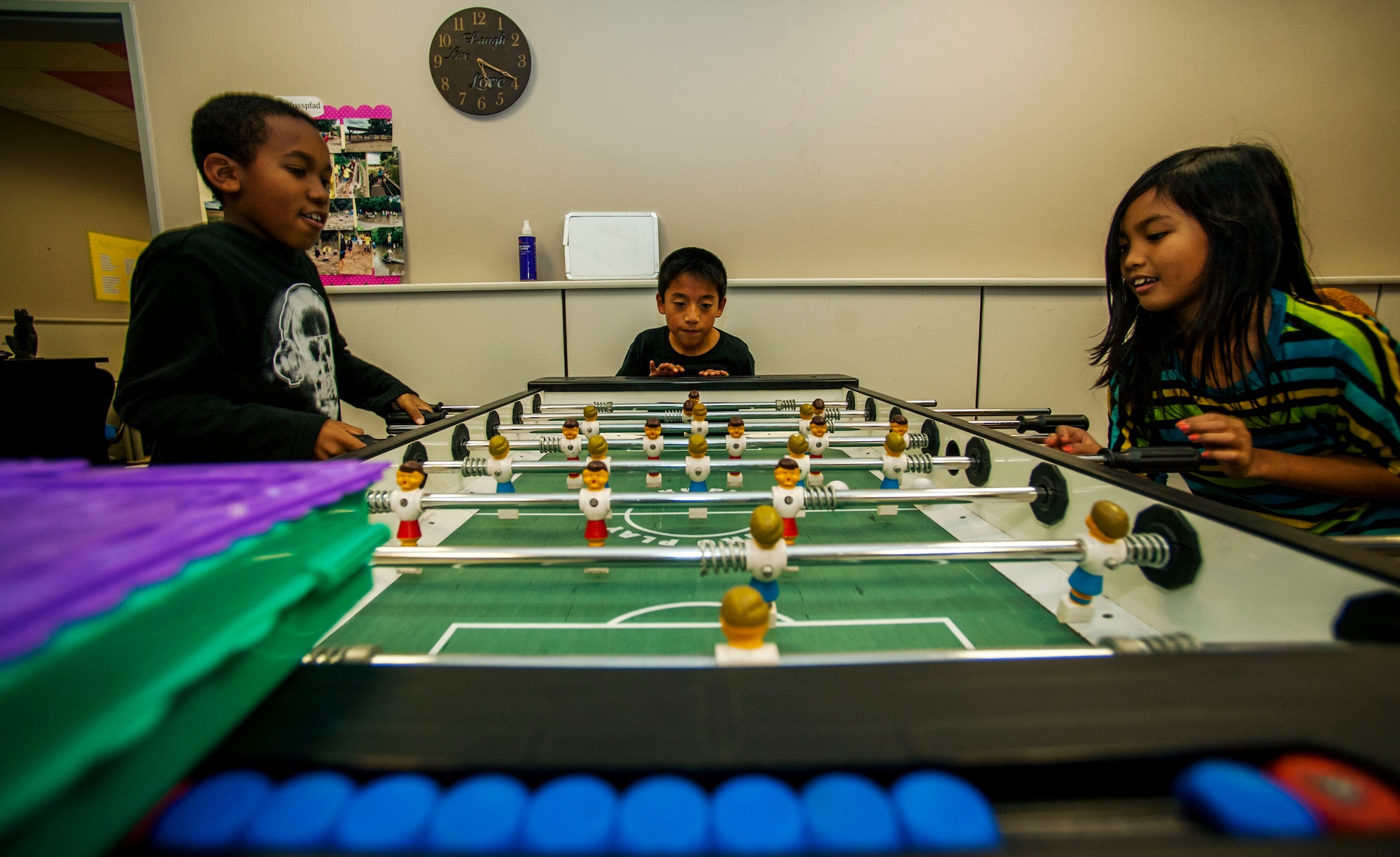Jayden Johnson, left, Augustin Stehley, center, and Jhen Li Bangi play a game of foosball during the Power Hour in the School Age Program building at Spangdahlem Air Base, Germany, Nov. 10, 2015. The facility contains various rooms designed to allow young students to socialize, explore their interests and play together. (U.S. Air Force photo by Airman 1st Class Timothy Kim/Released)