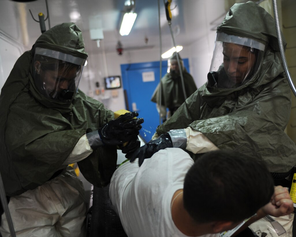Tech. Sgt. Dilcia Kammermeyer, 39th Medial Operations Squadron Preventive Dentistry non-commissioned officer in charge, and Senior Airman Natalia Mona, 39th MDOS public health technician, scrub Staff Sgt. Derek Williams, 39th MDOS Logistics technician, as part of the decontamination process during an exercise Oct. 28, 2015, at Incirlik Air Base Turkey. Medical personnel ensure that patients are completely decontaminated before being exposed to other personnel. (U.S. Air Force photo by Airman 1st Class Daniel Lile/Released)