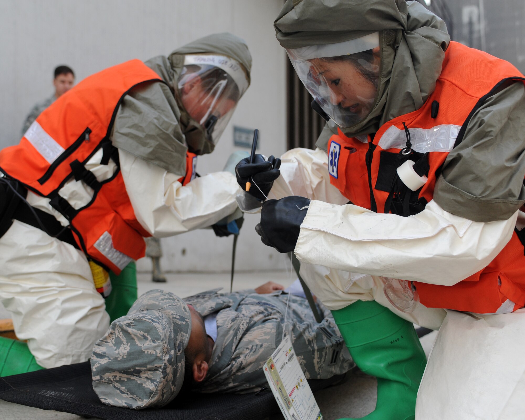 Maj. Melissa Tennant, 39th Medical Operations Squadron Physical Therapy officer, and Capt. Cindy Lan, 39th MDOS dentist, administer medical assistance to Airman 1st Class Xavier Jones, 39th MDOS public health technician, during an mass casualty exercise including potential chemical, biological, radiological and nuclear contamination Oct. 28, 2015, at Incirlik Air Base, Turkey. The medical personnel wear chemical protection equipment to avoid possible contamination. (U.S. Air Force photo by Airman 1st Class Daniel Lile/Released)