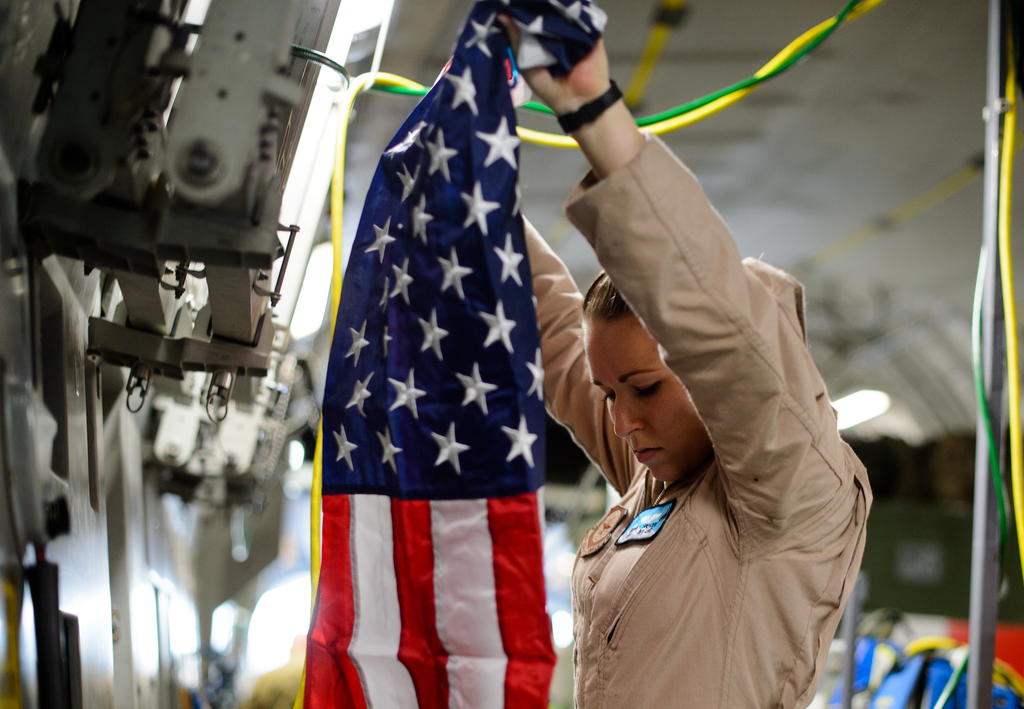 Senior Airman Beverly Spencer, 10th Expeditionary Aeromedical Evacuation Flight technician, hangs a flag inside a C-17 Globemaster III Nov. 10, 2015, at Ramstein Air Base, Germany. Spencer and crews from the 10th EAEF are deployed to Ramstein as a bridge between the deployed environment and medical facilities in the U.S. and Germany. Many Air Force aircraft conduct aeromedical evacuation, bringing the injured to the help they need. (U.S. Air Force photo/Staff Sgt. Armando A. Schwier-Morales)