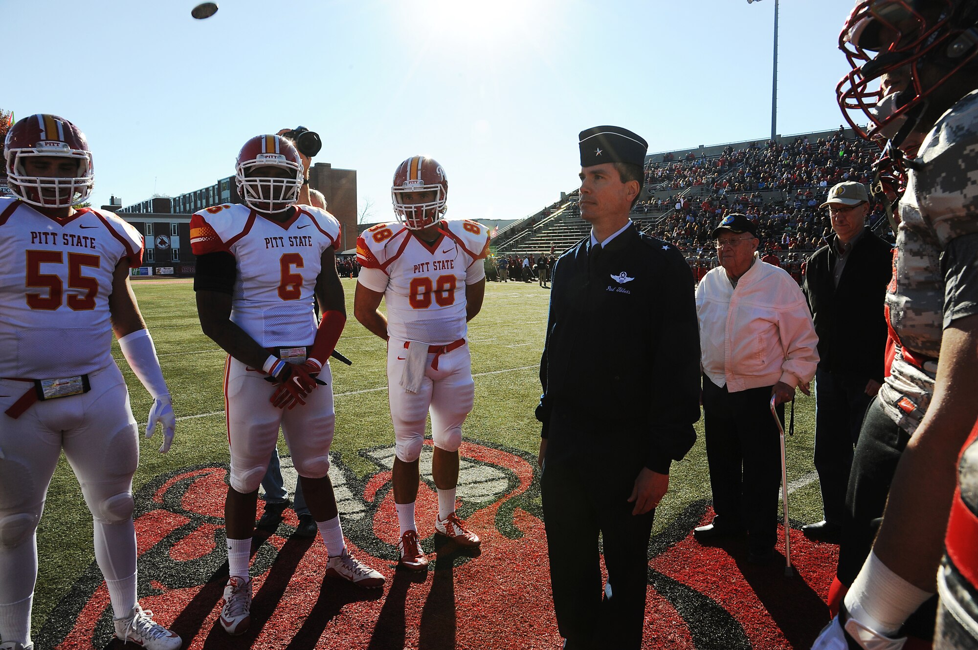 Members of the Pittsburg State University and University of Central Missouri (UCM) football teams look on as U.S. Air Force Brig. Gen. Paul Tibbets IV, the 509th Bomb Wing commander, performs a coin toss before the military appreciation football game at UCM in Warrensburg, Mo., Nov. 7, 2015. UCM hosted a military appreciation game to express gratitude to service members. (U.S. Air Force photo by Airman 1st Class Michaela R. Slanchik)