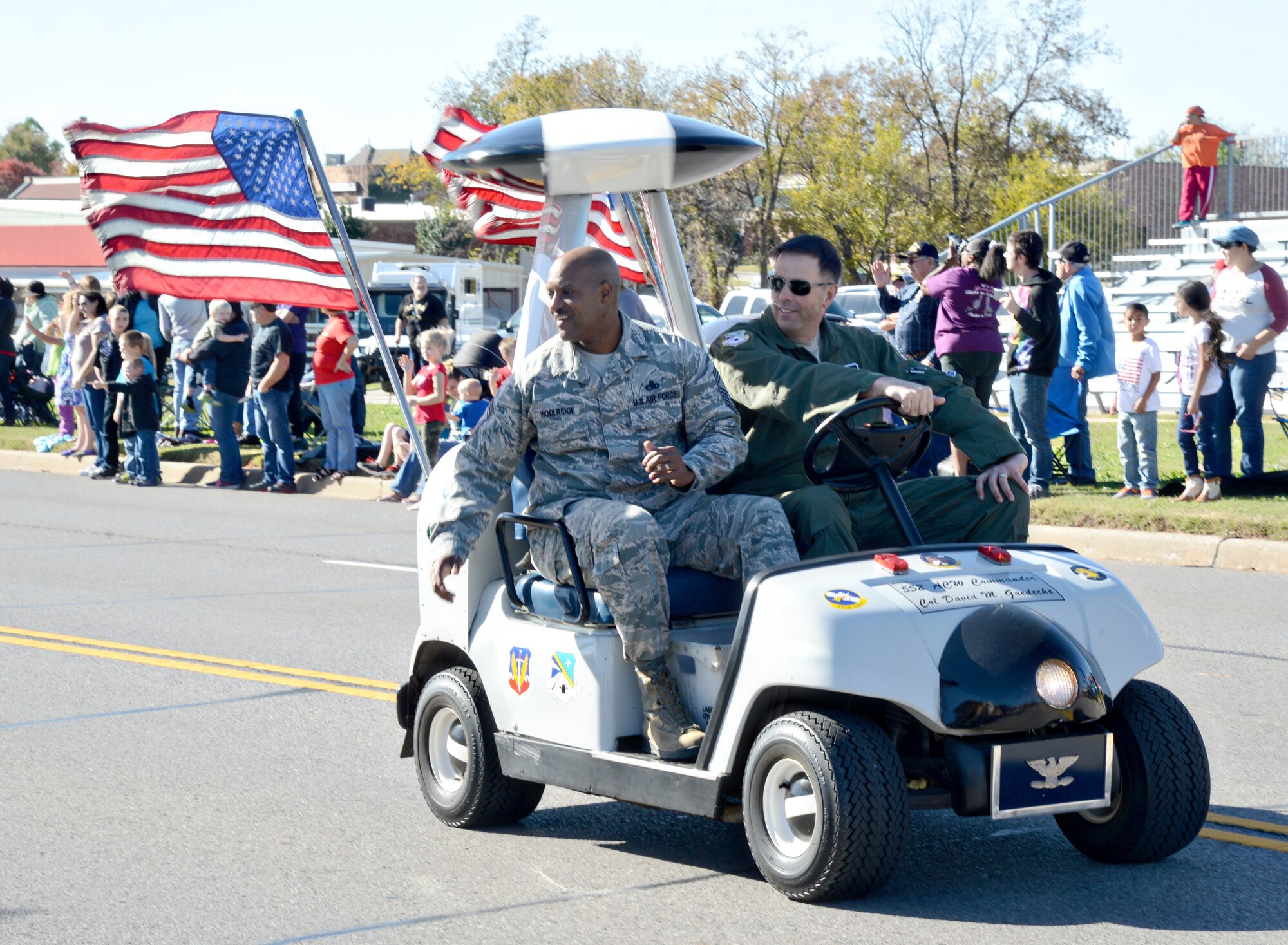 With 552nd Air Control Wing Vice Commander Col. Bradley Bird at the wheel, 552nd ACW Command Chief Master Sgt. Avery Woolridge throws candy as they drive down the parade route in their AWACS-modified golf cart.  (Air Force photo by Kelly White/Released)