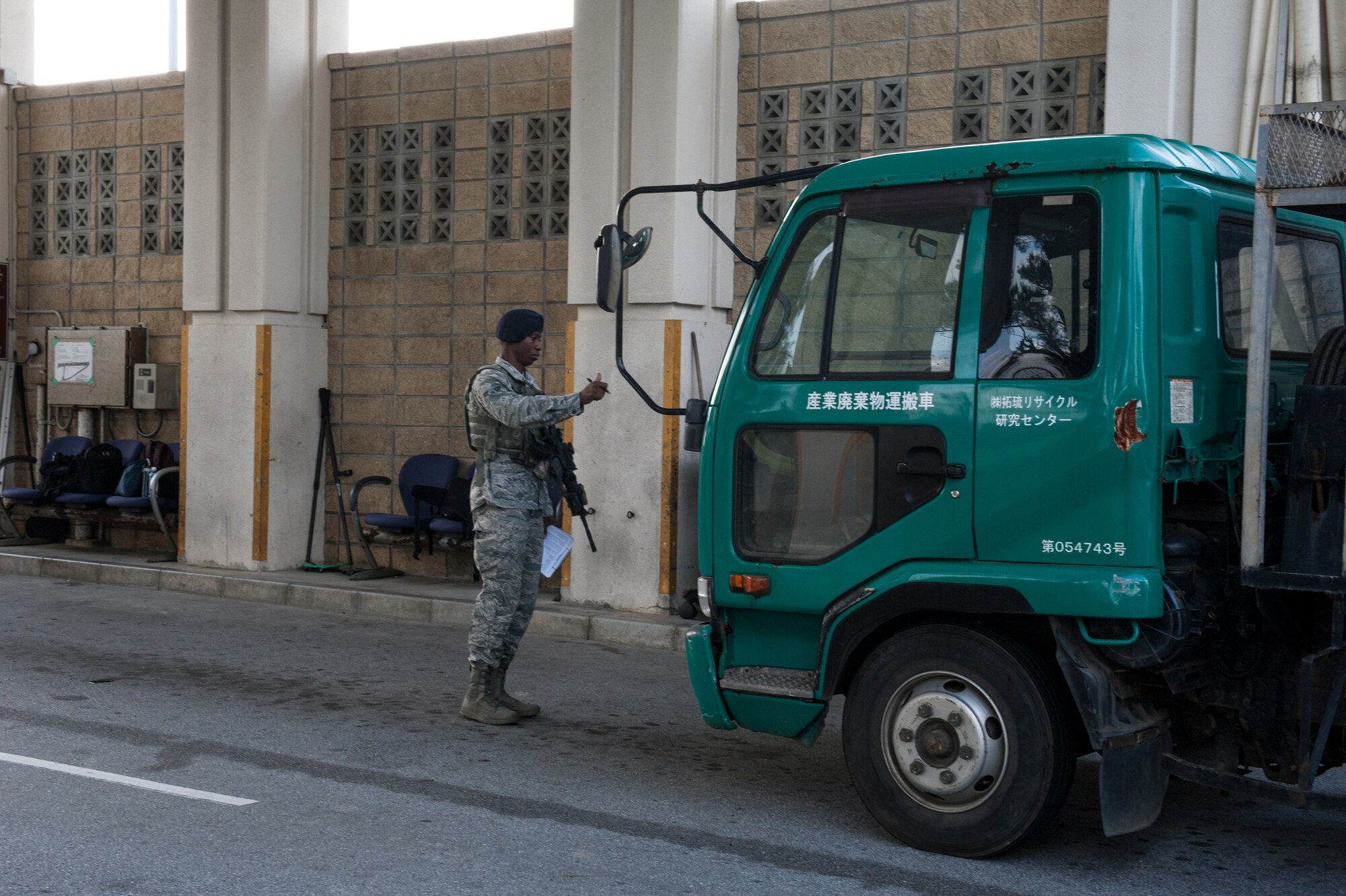 U.S. Air Force Airman 1st Class Alvin Stewart, 18th Security Forces Squadron response force member, directs a truck to a search pit at Kadena Air Base, Japan, Nov. 10, 2015. The SFS opened an extra lane for commercial trucks to enter and be searched in order to decrease traffic congestion on Highway 58. (U.S. Air Force photo by Airman 1st Class Lynette M. Rolen)