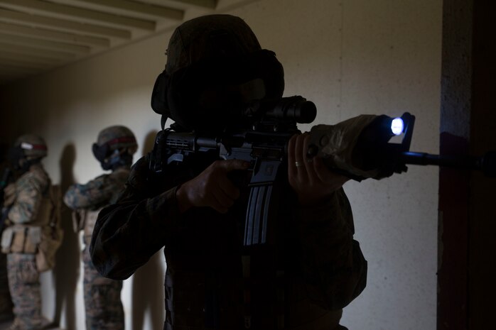 Cpl. Mark McNulty provides security while his fire team searches a Marine from the opposing side in Central Training Area’s Combat Town in Okinawa, Japan, Nov. 6, 2015. A fire team of Marines entered and cleared a building with special effect small-arms marking system rounds with an opposing force hiding a hostage. The scenario was conducted on the final day of a three day training event aimed at improving skills clearing buildings. McNulty is from Scranton, Pennsylvania, and is a military policeman with Military Police Detachment, Combat Logistic Battalion 31, 31st Marine Expeditionary Unit. 