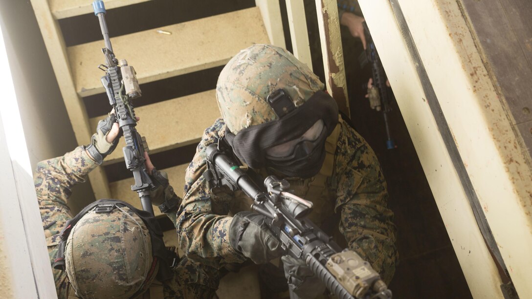 Lance Cpl. Alex Mann, left, and Cpl. Robert Sweeny, right, clear a stairway before entering the second floor as their fire team clears a building Central Training Area’s Combat Town in Okinawa, Japan, Nov. 6, 2015. An opposing force hid in the building with a hostage and both sides had special effect small-arms marking system rounds. Mann is from Dunstable, Massachusetts and Sweeny is from Jefferson, New Jersey. Both are military policemen with Military Police Detachment, Combat Logistic Battalion 31, 31st Marine Expeditionary Unit. 