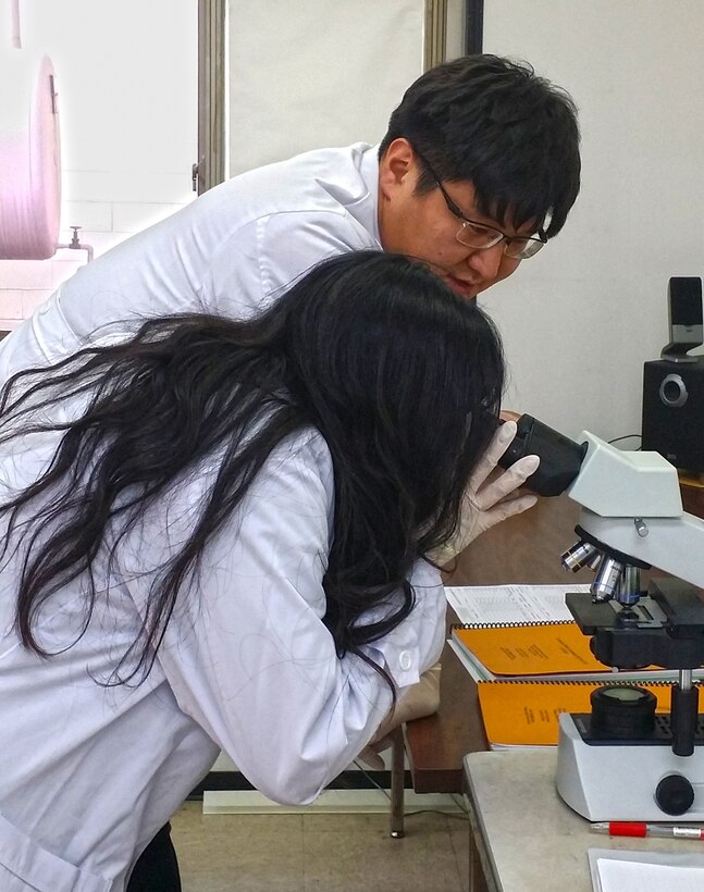 Mr. Kyong-Ho Kim demonstrates microscope analysis to Kelly Wu, showing how the presence of asbestos fibers are identified in the laboratory. Ms. Wu is a senior at Seoul American High School, and shadowed Far East District staff members on Nov. 5, 2015 to learn more about what they do. Mr. Kim is a chemist in the geotechnical and environmental engineering branch of the Far East District of the U.S. Army Corps of Engineers.  (Photo courtesy of Dr. Son-Chu Chon, U.S. Army Corps of Engineers)
