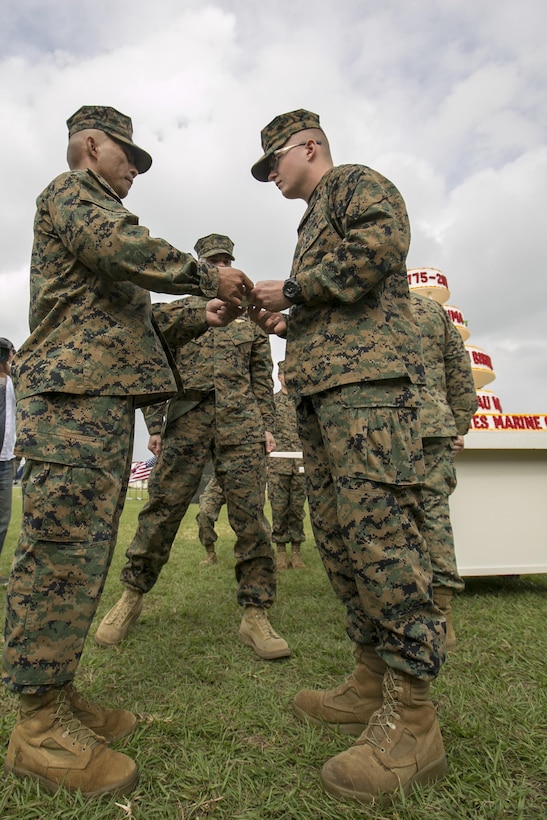 Master Gunnery Sgt. Eli Ginez hands the first slice of cake to Lance Cpl. Cory Booher during the Marine Corps birthday cake cutting Nov. 10 aboard Camp Foster, Okinawa, Japan. “The passing of the cake from the oldest to the youngest Marine symbolizes the passing of history and traditions to the next generation,” read the narrator as the cake was shared by the two Marines. Ginez, senior enlisted advisor with Installations Personnel Administration Center, and Booher, a postal finance clerk, are both Marines with Headquarters and Support Battalion, Marine Corps Installations Pacific, Marine Corps Base Camp Smedley D. Butler.