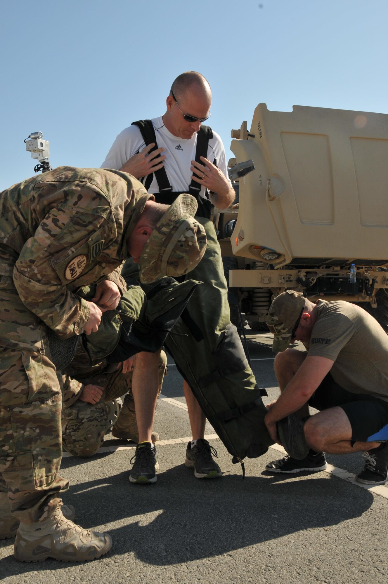 Explosive ordnance disposal technicians assigned to the 379th Expeditionary Civil Engineer squadron assist Brig. Gen. Darren James, 379th Air Expeditionary Wing commander, with putting on a bomb suit Nov. 14 at Al Udeid Air Base, Qatar. James wore the suit during the Month of the Military Family's November walk sponsored by the Airman and Family Readiness Center. (U.S. Air Force photo by Tech. Sgt. Terrica Y. Jones/Released)