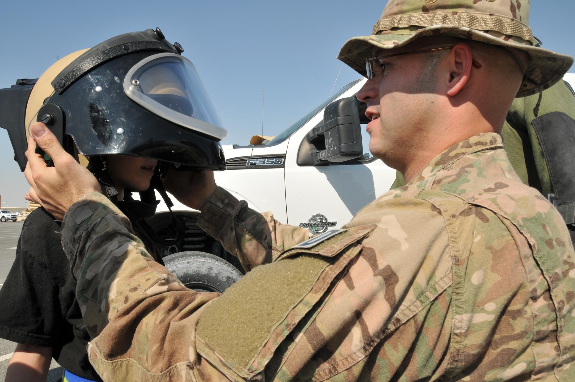 Explosive ordnance disposal technicians assigned to the 379th Expeditionary Civil Engineer squadron talks about the F6-robot at the military family event Nov. 14 at Al Udeid Air Base, Qatar. Family members also received a chance to wear the EOD-9 bomb suit helmet. (U.S. Air Force photo by Tech. Sgt. Terrica Y. Jones/Released)