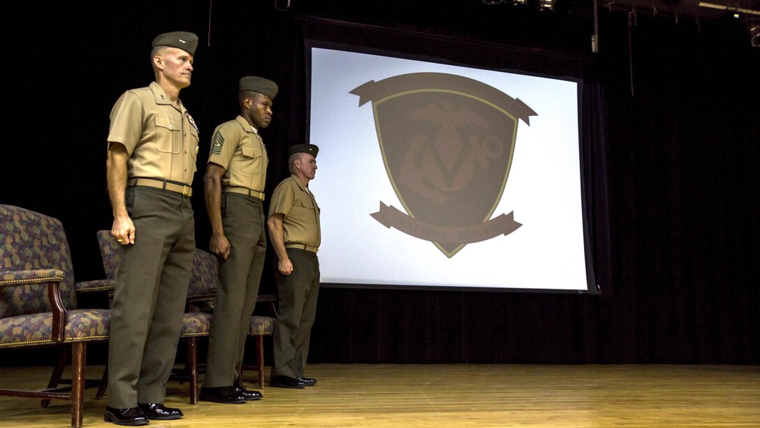 From left, U.S. Marine Corps Maj. Gen. Carl E. Mundy III, commanding general of the 5th Marine Expeditionary Brigade, Sgt. Maj. Clifford W. Wiggins, sergeant major of the 5th Marine Expeditionary Brigade, and U.S. Navy Cmdr. Steven D. Mills, chaplain of the 5th Marine Expeditionary Brigade, stand during the playing of the Marines Hymn at the 5th MEB activation ceremony at Naval Support Activity Bahrain, Oct. 15, 2015. The unit, formerly known as Command Element Marine Corps Forces Command, Central Command Forward, was re-designated as the 5th MEB to more accurately reflect Marine Corps organizational doctrine, and will continue to provide a forward-deployed headquarters in the U.S. Central Command area of responsibility.
