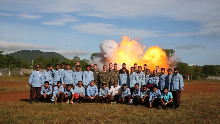 Explosive ordinance disposal U.S. Marines and Cambodian Mine Action Center technicians pose for a picture in front of exploding ordinance at Kampong Chhnang, in the Kingdom of Cambodia, Nov. 5, 2015. U.S Marine EOD trained CMAC in support of the Humanitarian Mine Action program. The program focuses on assisting selected countries in relieving human suffering and in developing an indigenous mine action capability to help with explosive remnants of war. 