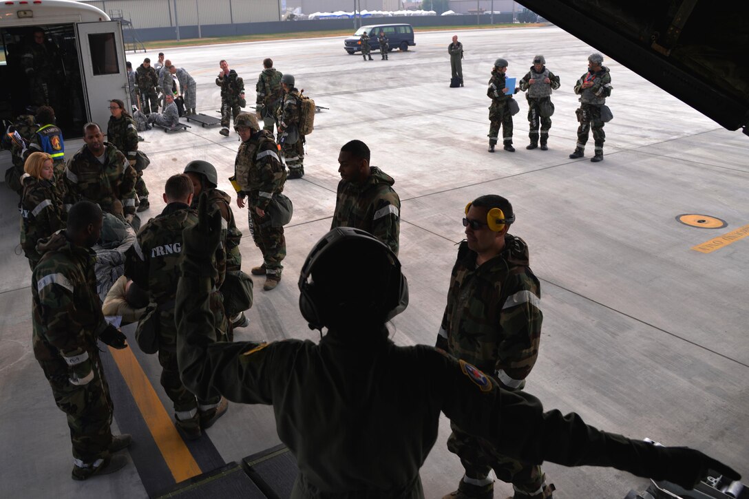 A U.S. airman, foreground, directs airmen participating in Vigilant Ace 16 to load a simulated casualty into an HC-130 Combat King II cargo aircraft on Osan Air Base, South Korea, Nov. 5, 2015. The airman is assigned to the 18th Aeromedical Evacuation Squadron. U.S. Air Force photo by Staff Sgt. Benjamin Sutton