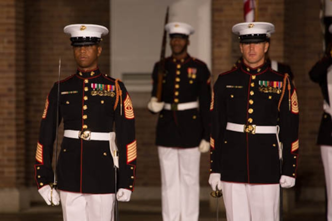 Master Gunnery Sergeant Kevin Buckles (left), Drum Major of the United States Marine Drum and Bugle Corps, leads the parade staff at the retirement ceremony of Sergeant Major James E. Booker. Master Sergeant Keith Martinez, assistant drum major, pictured on the right, served as adjutant for the ceremony.