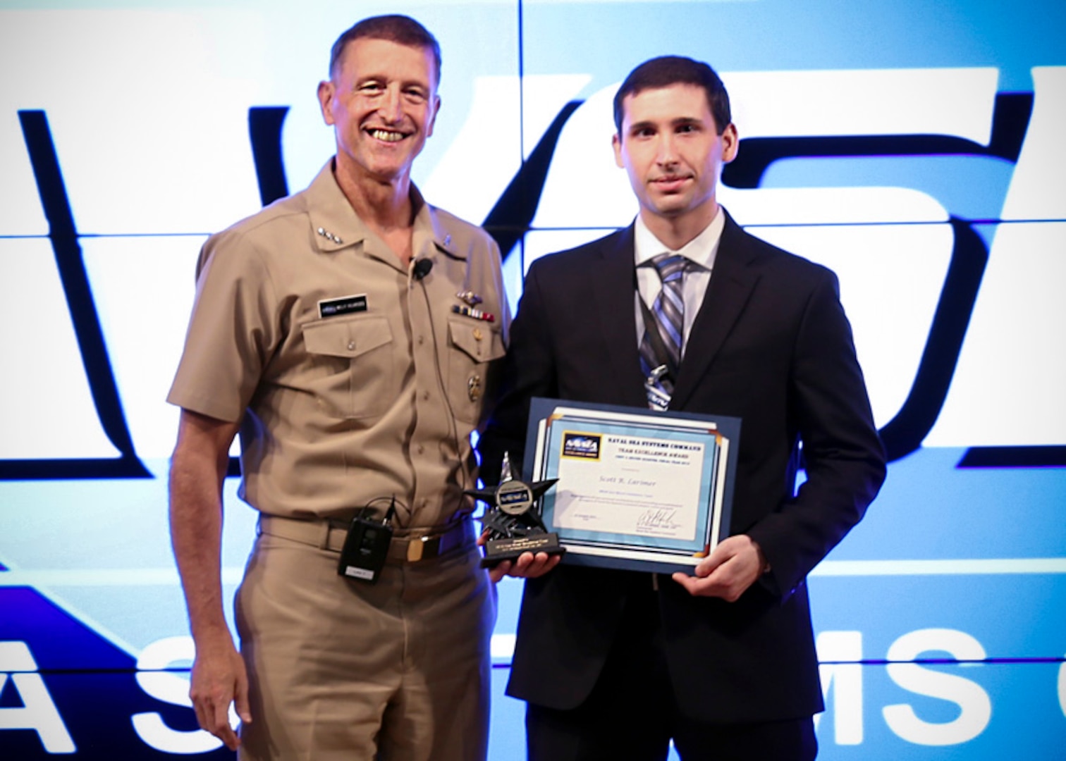 Scott Larimer accepts the NAVSEA Team Excellence Award for the MK45 Gun Mount Installation and Checkout Team from NAVSEA Commander Vice Adm. William Hilarides during a ceremony, Oct. 27.