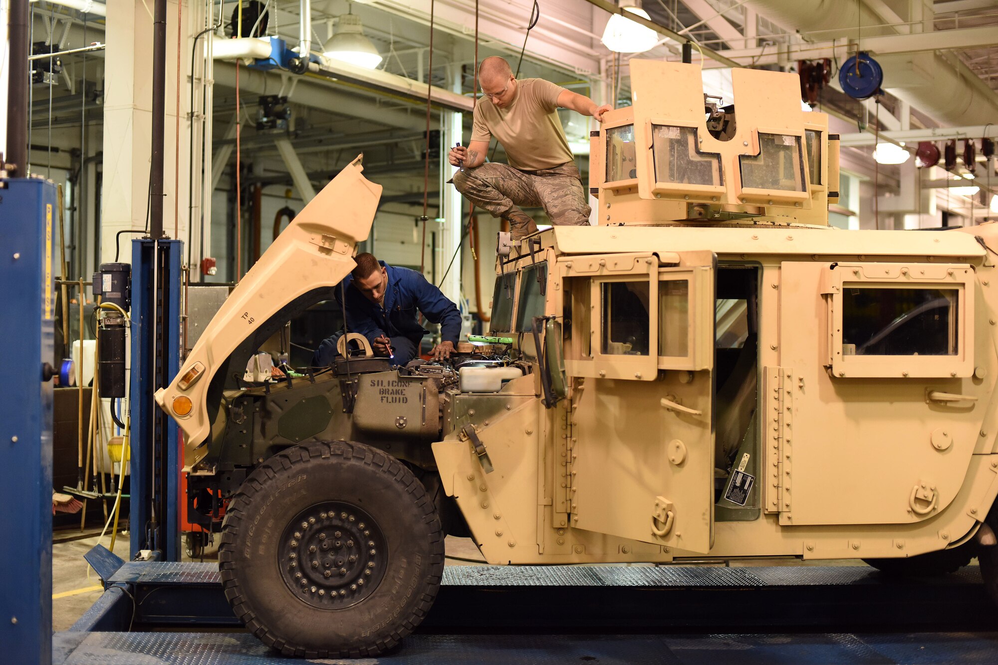 Senior Airman Elliott Packingham, 341st Logistics Readiness Squadron fleet management analyst, shines a light for Senior Airman Zachary Simmons, 341st LRS vehicle maintenance journeyman, as he makes repairs to a Humvee during exercise GLOBAL THUNDER 16, Nov. 6, 2015 at Malmstrom Air Force Base, Mont. The 341st LRS is part of U.S. Strategic Command’s (USSTRATCOM) Task Force 214 and supports the command’s strategic deterrence mission by operating and maintaining the Air Force’s Intercontinental Ballistic Missile force. GLOBAL THUNDER is an annual U.S. Strategic Command training event that assesses command and control functionality in all USSTRATCOM mission areas and affords component commands a venue to evaluate their joint operational readiness. Planning for GLOBAL THUNDER 16 has been under way for more than a year and is based on a notional scenario with fictitious adversaries. USSTRATCOM, one of nine DoD unified combatant commands, relies on various task forces for the execution of its global missions, which also include space operations; cyberspace operations; joint electronic warfare; global strike; missile defense; intelligence, surveillance and reconnaissance; combating weapons of mass destruction; and analysis and targeting. (U.S. Air Force photo by Airman Collin Schmidt) 