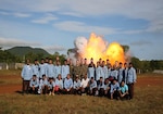 Explosive ordinance disposal U.S. Marines and Cambodian Mine Action Center technicians pose for a picture in front of exploding ordinance at Kampong Chhnang, in the Kingdom of Cambodia, Nov. 5, 2015. U.S Marine EOD trained CMAC in support of the Humanitarian Mine Action program. The program focuses on assisting selected countries in relieving human suffering and in developing an indigenous mine action capability to help with explosive remnants of war. 