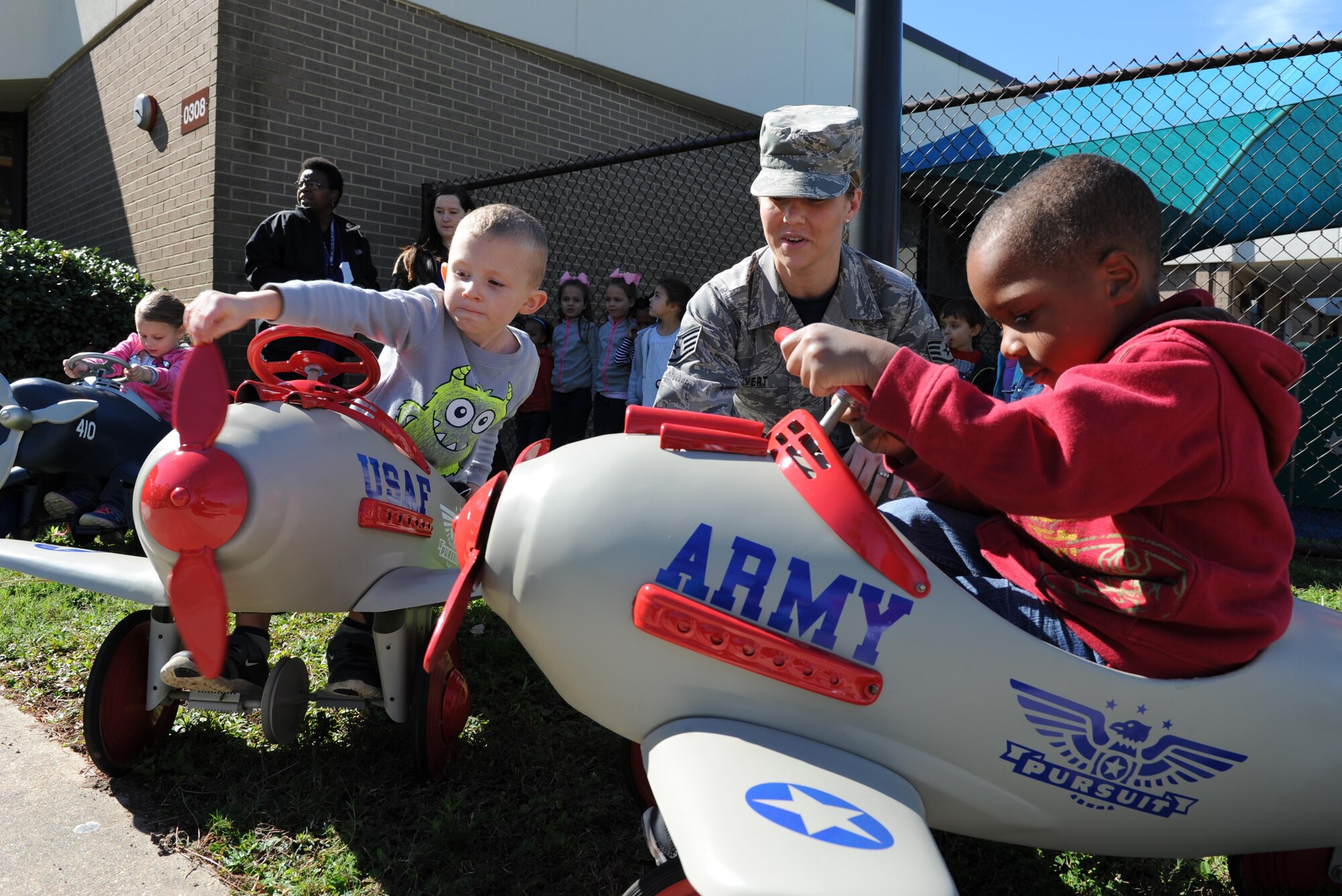 Staff Sgt. Valerie Divert, 81st Training Support Squadron customer support, assists children at the child development center as they play with the newly refurbished pedal airplanes Nov. 13, 2015, Keesler Air Force Base, Miss. The four pedal airplanes, refurbished by the Trainer Development Center, have been in storage for more than 10 years. Divert and the Keesler parent advisory board spearheaded the project. (U.S. Air Force photo by Kemberly Groue)