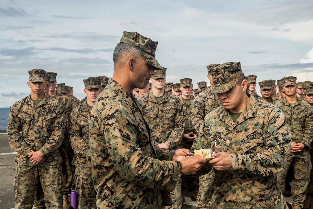 SOUTH CHINA SEA (Nov. 9, 2015) U.S. Marine Lt. Col. Wilfred Rivera, left, passes a piece of birthday cake to Lance Cpl. Manuel Davalos during the Marine Corps birthday ceremony aboard USS Rushmore (LSD 47). Rivera is the commanding officer of Combat Logistics Battalion 15, 15th Marine Expeditionary Unit. Davalos is a rifleman with Kilo Company, Battalion Landing Team 3rd Battalion, 1st Marine Regiment, 15th MEU. During the ceremony, it is customary for the oldest and youngest Marines present to enjoy the first slice of cake signifying the passing of traditions. The 15th MEU is currently deployed in the Indo-Asia-Pacific region to promote regional stability and security in the U.S. 7th Fleet area of operations. (U.S. Marine Corps photo by Sgt. Emmanuel Ramos/Released)