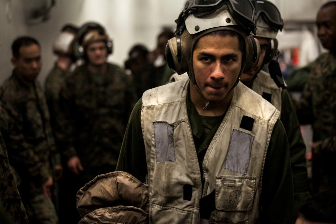 SOUTH CHINA SEA (Nov. 13, 2015) A U.S. Marine with the 15th Marine Expeditionary Unit passes out flotation devices to Marines waiting to load an aircraft aboard the USS Essex (LHD 2). The 15th MEU is currently deployed in the Indo-Asia-Pacific region to promote regional stability and security in the U.S. 7th Fleet area of operations. (U.S. Marine Corps photo by Cpl. Elize McKelvey/Released)