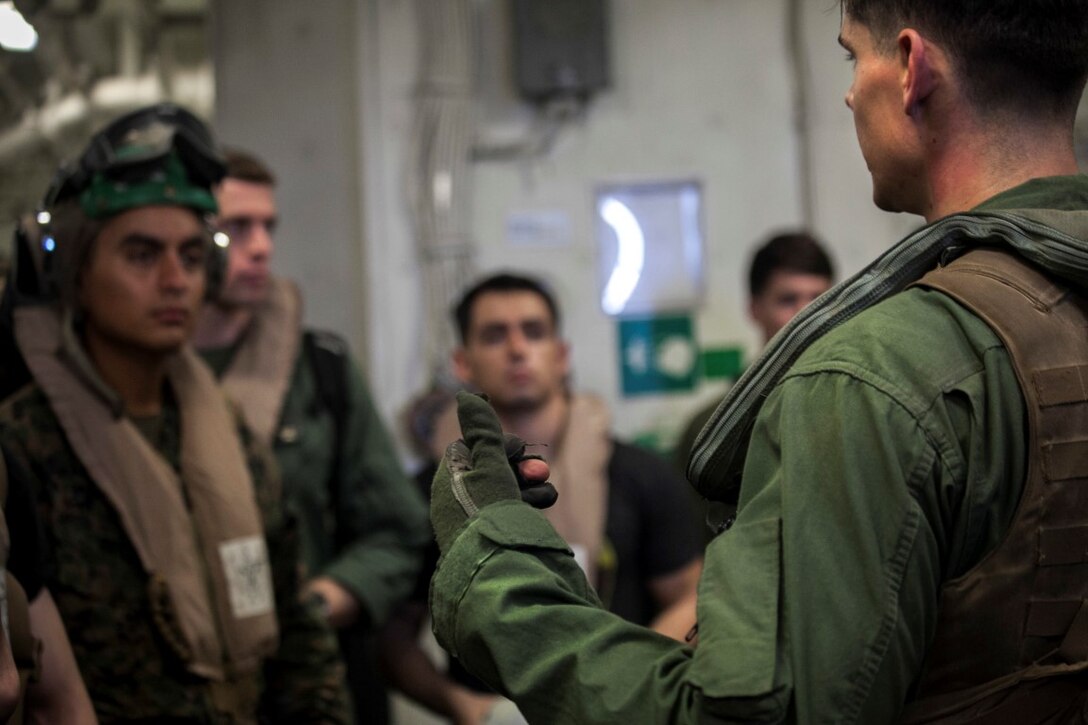 SOUTH CHINA SEA (Nov. 13, 2015)  A U.S. Marine with the 15th Marine Expeditionary Unit gives instructions on how to use the safety gear prior to loading an MV-22B Osprey aboard the USS Essex (LHD 2). The 15th MEU is currently deployed in the Indo-Asia-Pacific region to promote regional stability and security in the U.S. 7th Fleet area of operations. (U.S. Marine Corps photo by Cpl. Elize McKelvey/Released)