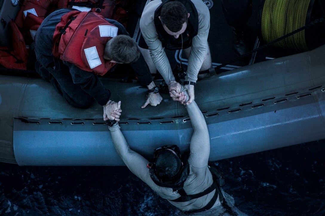 SOUTH CHINA SEA (Nov. 15, 2015) A U.S. Sailor with the Essex Amphibious Ready Group is pulled out of the water during a transition of safety divers during a swim call aboard the USS Essex (LHD 2). The Marines and Sailors of the 15th Marine Expeditionary Unit and Essex ARG jumped 30-feet into the water and swam to their respective check point. The 15th MEU is currently deployed in the Indo-Asia-Pacific region to promote regional stability and security in the U.S. 7th Fleet area of operations. (U.S. Marine Corps photo by Cpl. Elize McKelvey/Released)