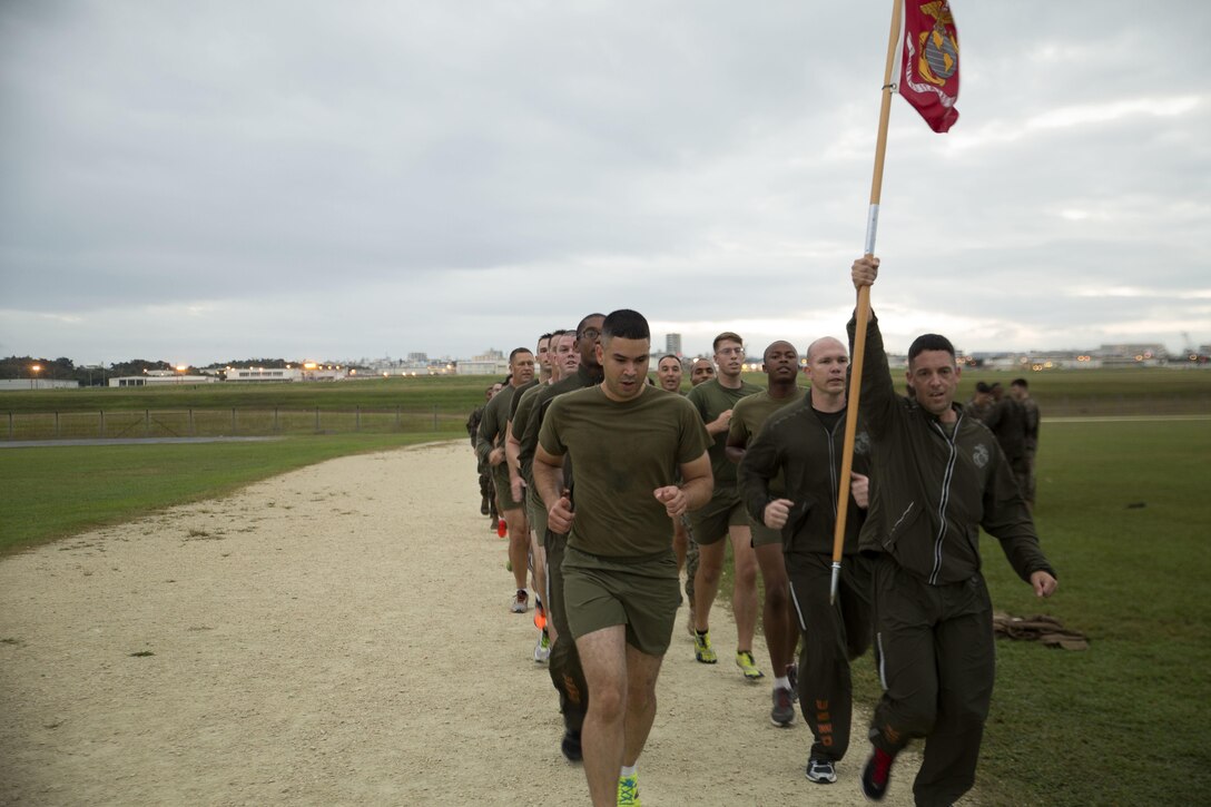 Master Sgt. Jason Annis raises the guidon in celebration as the Marines finish 240 laps around the Semper Fit track Nov. 10 on Marine Corps Air Station Futenma, Okinawa, Japan. The Marines ran the laps to celebrate the 240th Marine Corps Birthday. It took the Marines over seven hours to finish. Annis is the communications chief for MCAS Futenma S-6, Communications, Marine Corps Installations Pacific.