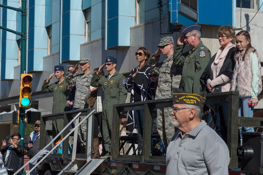 Sheppard Air Force Base leaders salute Airmen marching by in the Veterans Day parade in downtown Wichita Falls, Nov. 7, 2015. Several flights of Airmen participated in the parade, marching with flags and playing patriotic music for the people of Wichita Falls. (U.S. Air Force photo/Senior Airman Kyle Gese)