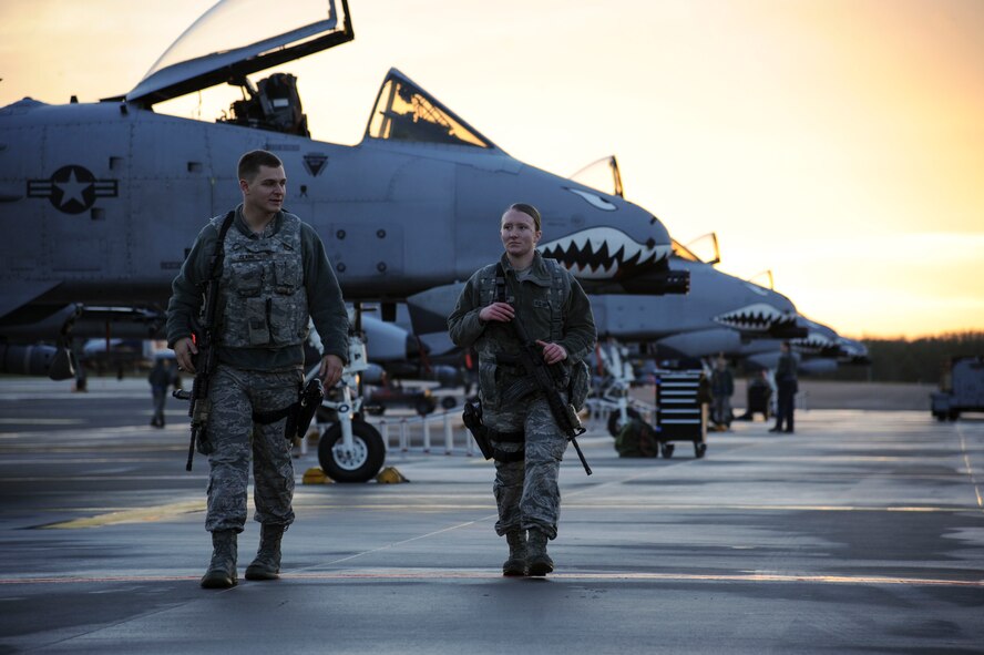 Two U.S. Air Force security forces Airmen walk the flightline at Amari Air Base, Estonia, Nov. 3, 2015. These security forces Airmen are part of the 74th Expeditionary Fighter Squadron Base Operations Support-Integrating team and are deployed from Spangalhem Air Base, as part of a theater security package in support of Operation Atlantic Resolve.  (U.S. Air Force photo by Andrea Jenkins/Released).
