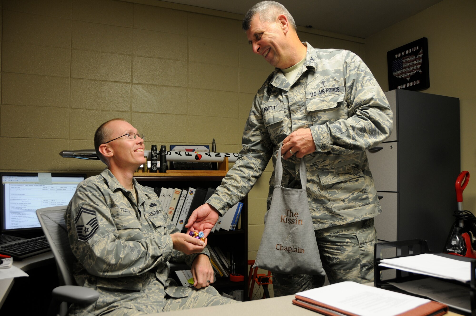 Chaplain (Col.) Thomas Smith, Arkansas Joint Force Headquarters command chaplain, provides Senior Master Sgt. Ray Traylor, 188th Weapons Safety manager, with Hershey’s Hugs and Kisses at Ebbing Air National Guard Base, Fort Smith, Ark., Oct. 7, 2015. Smith has served the 188th Wing for more than 20 years as a wing chaplain and the full-time base chaplain. Smith has served for 10 years overseas in the Philippines as a missionary and has pastored for 40 years. With more than 45 years preaching, Smith brings diverse experience and knowledge to the Arkansas Air National Guard and continues to mentor Airman and Soldiers as he serves at Arkansas JFHQ. (U.S. Air National Guard photo by Staff Sgt. Hannah Dickerson/Released)