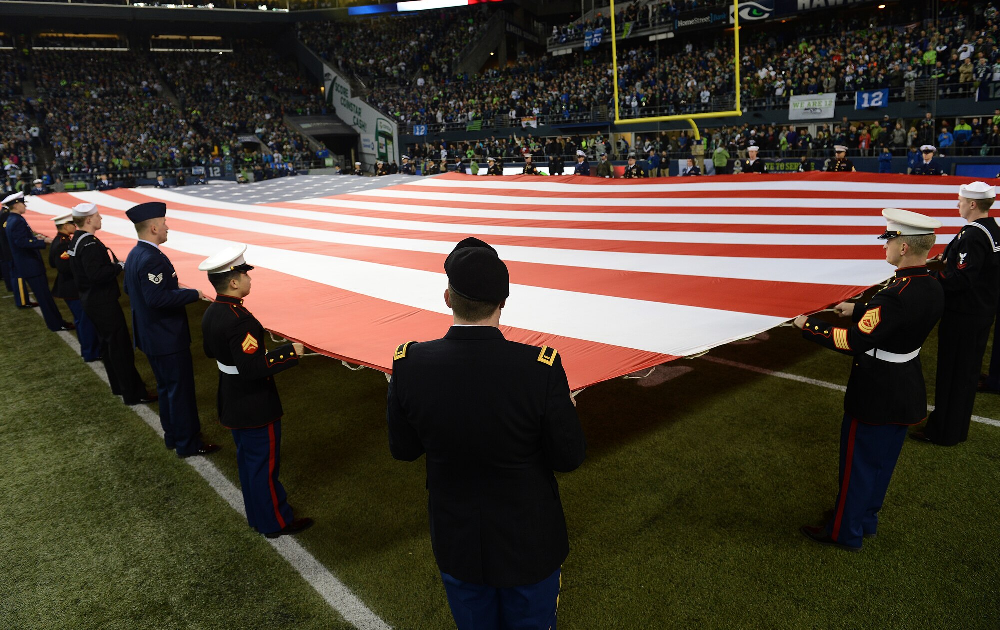 More than 100 service members hold the American flag during the national anthem at the start of the Seattle Seahawks vs. the Arizona Cardinals football game, Nov. 15, 2015, in Seattle, Wash. Military members participated in the opening ceremony and half-time presentation at Century Link field during the “Salute to Service” football game. (U.S. Air Force photo/Senior Airman Divine Cox)
