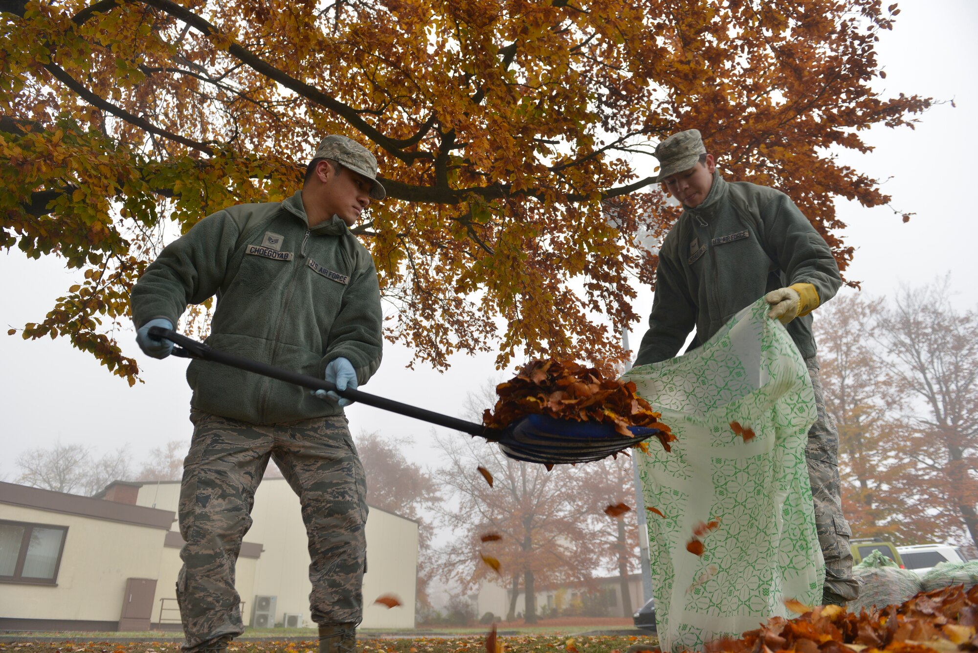 Staff Sgt. Tenzin Choegoyab and Airman 1st Class Ahmad Yehudah, both 86th Airlift Wing Command Post emergency action controllers, scoop up leaves during Base Pride Day Nov. 3, 2015, at Ramstein Air Base, Germany. Airmen and civilians around Ramstein were tasked to clean around their working areas during the biannual occasion. The two-day event gave Airmen and civilians time to clean-up by raking leaves and picking up trash to beautify the base.  (U.S. Air Force photo/Airman 1st Class Lane T. Plummer)