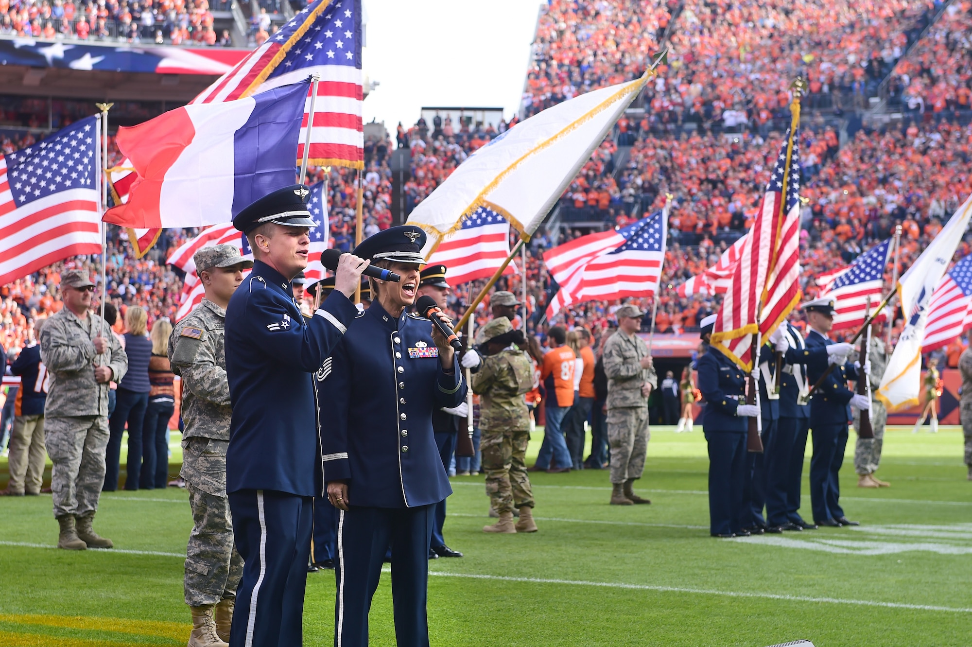 Two members of the U.S. Air Force sing the National Anthem Nov. 15, 2015, at Sports Authority Field at Mile High Stadium, Denver. The Denver Broncos hosted military members at their Salute to Service game against the Kansas City Chiefs. (U.S. Air Force photo by Airman 1st Class Luke W. Nowakowski/Released)